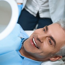 Man smiling in the mirror at the dentist