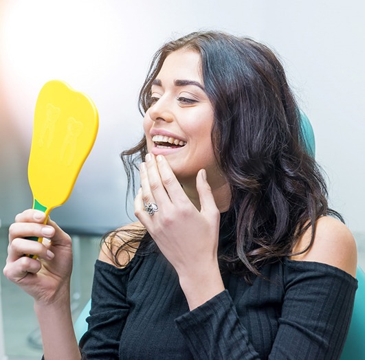 Dental patient looking at her smile in a mirror