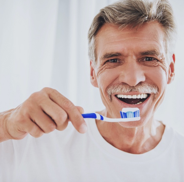 Older man with dentures brushing teeth
