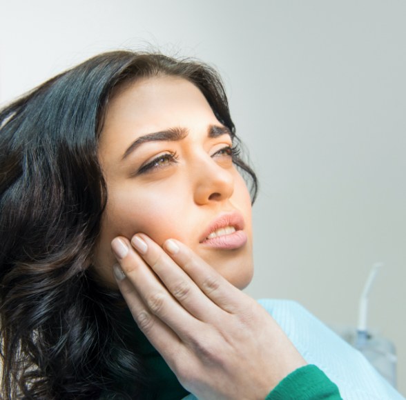 Woman in need of emergency dentistry holding cheek in pain