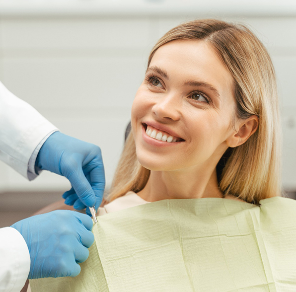 Female patient sitting and smiling up at dentist