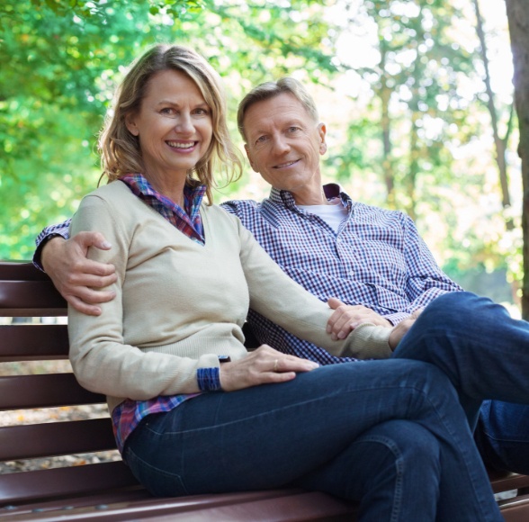 Older couple smiling after dental implant denture placement