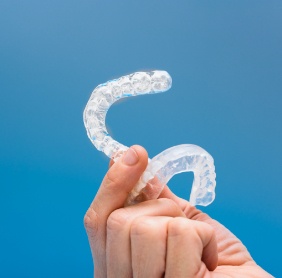 Hand holding up clear protective trays used for bruxism