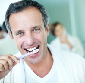 Man brushing teeth after dental implant surgery