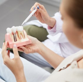 Dentist and patient looking at tooth model during initial dental implant consultation