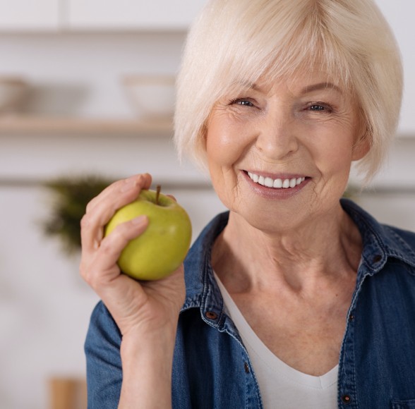 Woman eating an apple after dental implant placement