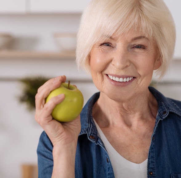 Woman eating an apple after dental implant placement
