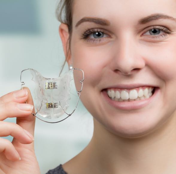 Young woman holding up a retainer