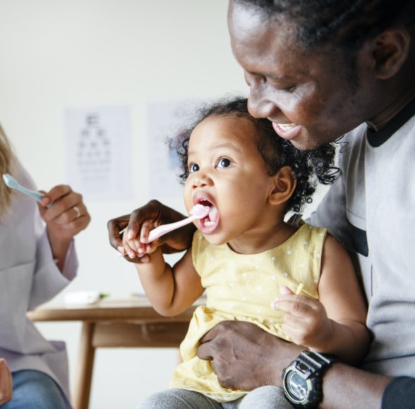 Father brushing child's teeth during children's dentistry visit