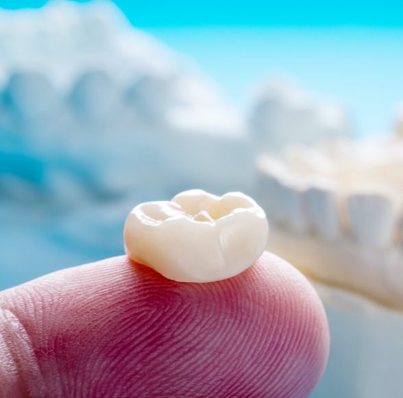 Dental crown resting on fingertip