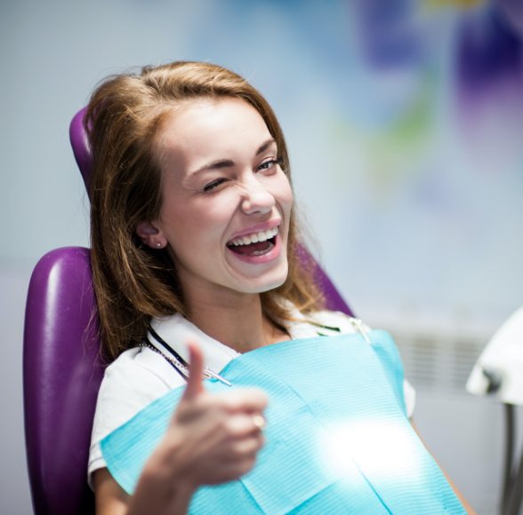 Woman giving thumbs up after dental sealant application