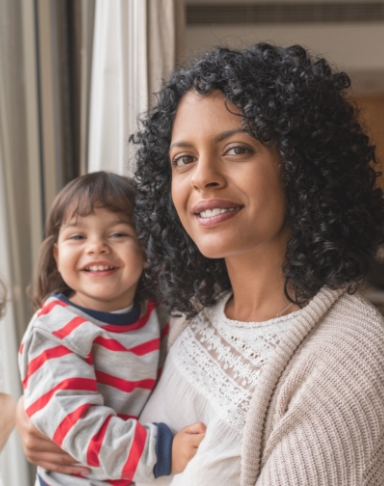 Mother holding smiling toddler after chldren's dentistry visit