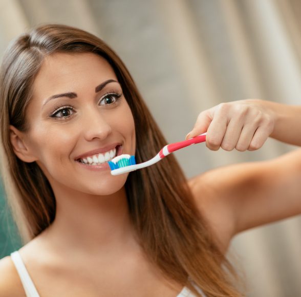 Woman brushing teeth to care for fillings