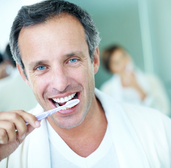 Man brushing teeth to care for dental veneers