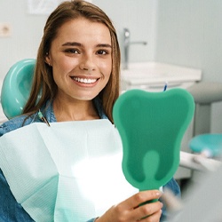 Dental patient with mirror, admiring the results of her cosmetic treatment