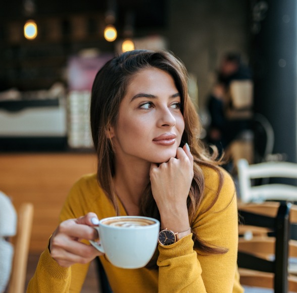Woman drinking coffee which causes dental stating prior to teeth whitening
