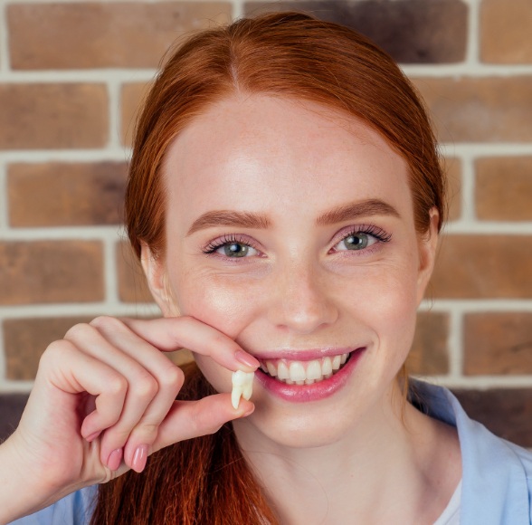Woman holding up extracted wisdom tooth