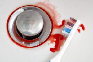 bloody toothbrush laying in bathroom sink