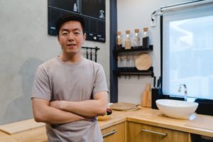 person standing in their kitchen and crossing their arms