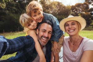 family of four smiling in the sunlight 