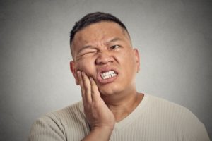 Pained man holds hand to his face because of a toothache