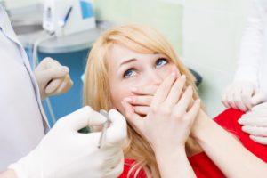 Woman with dental anxiety covers her mouth at checkup