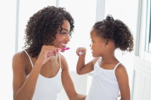 mother and daughter brushing their teeth together 