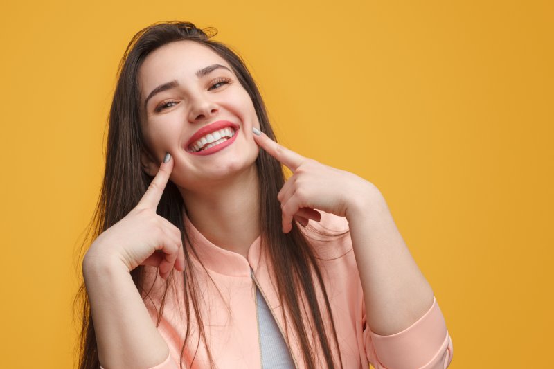 young woman pointing to her smile