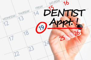 Hand writing dental appointment on white calendar 