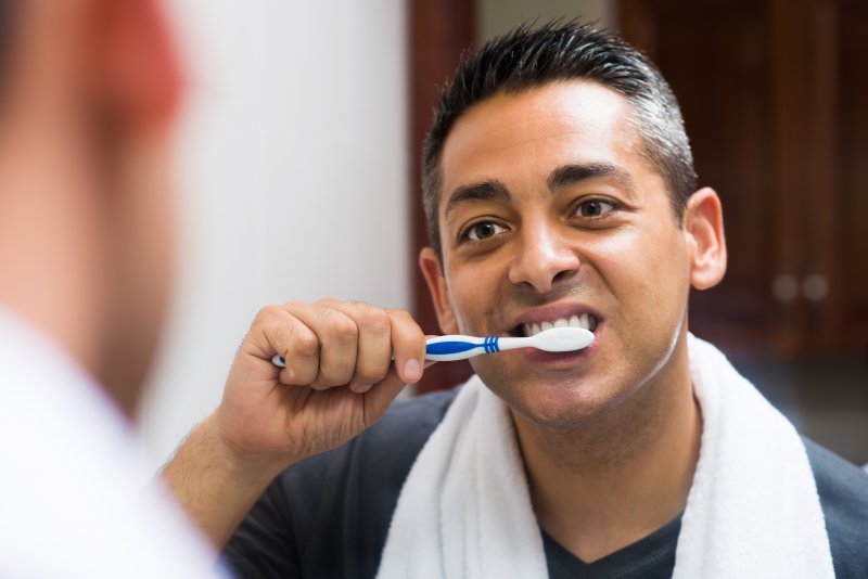 a man with dental implants brushing his teeth