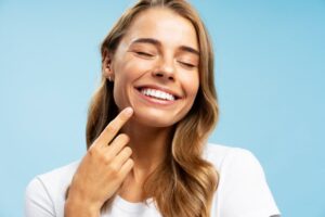 Woman with veneers pointing to her smile